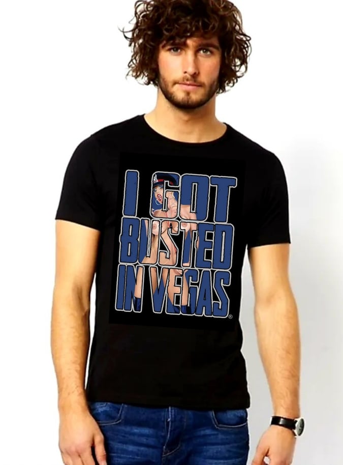 Black tee shirt with "I GOT BUSTED IN VEGAS" in blue, outlined in gray. Within the letters are an image of a woman wearing nothing but a black hat and black boots. Rated Adult.