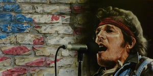 A slightly blurred Bruce Springsteen is shown from the shoulders up, facing towards the left, singing passionately into a microphone, wearing a red bandana around his forehead and a heavy jacket. In the background are white bricks and on the left a faded spray paint American flag.