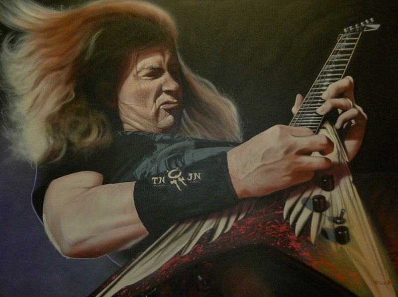 Dave Mustaine is shown passionately playing the guitar. He is wearing a black t-shirt and his hair is flying behind him as he presumably is sliding across the floor.The guitar is triangular and red, with white angel wings on it. The sweatband on his wrist reads "TN JN."